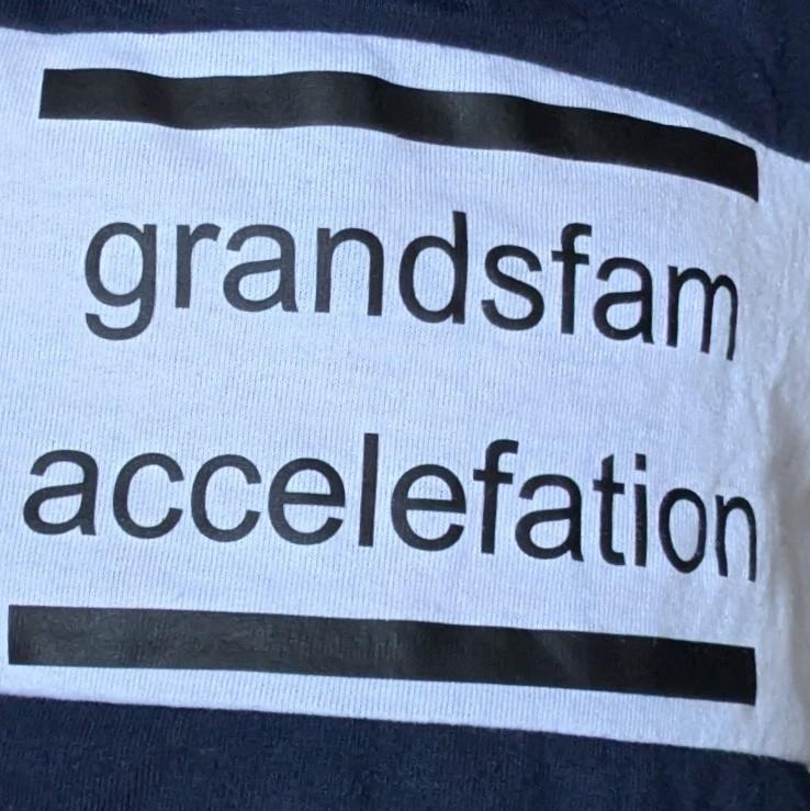 A closer photograph of a child's t-shirt. Printed on it is: grandsfam accelefation.