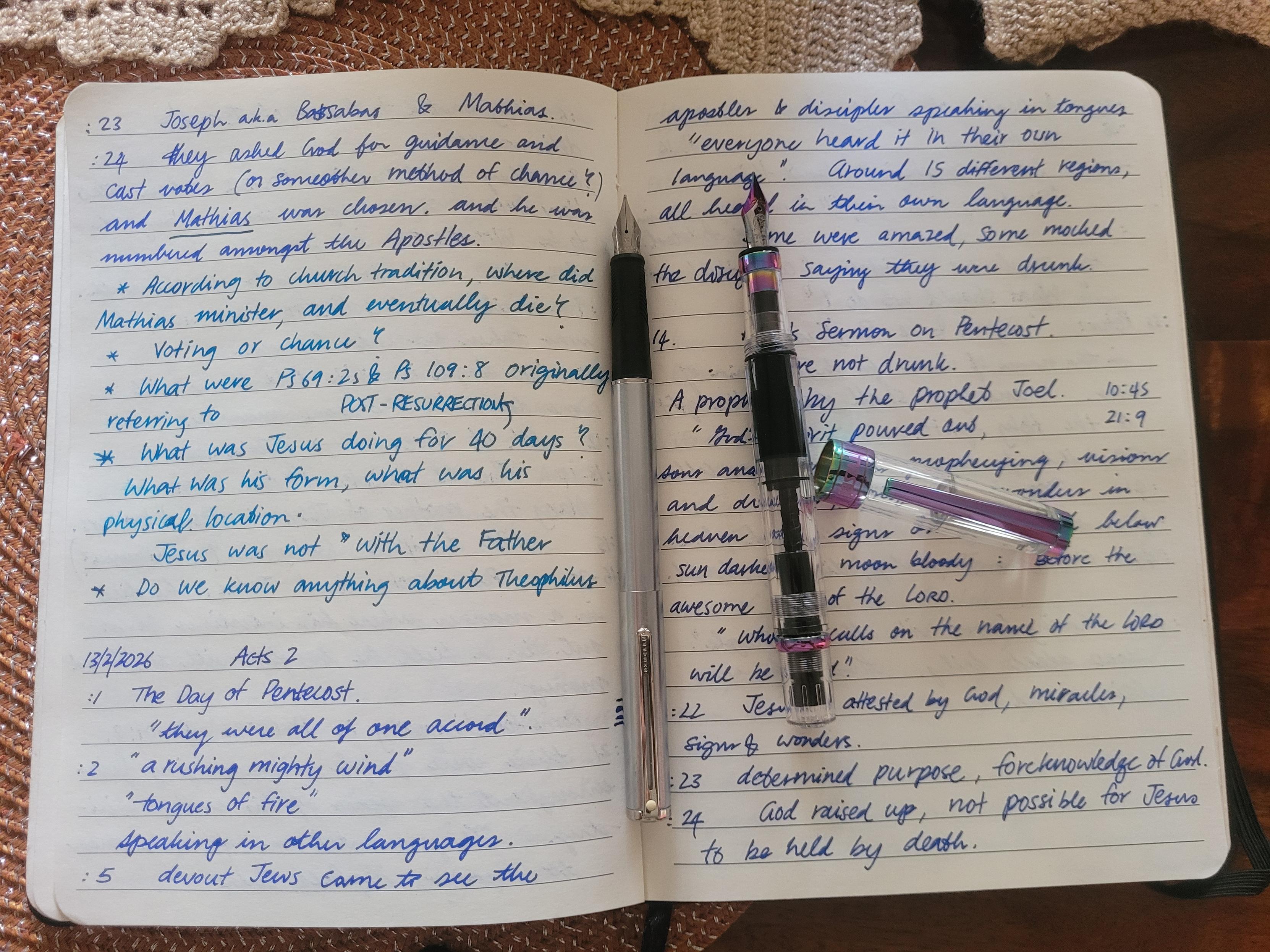 Two uncapped fountain pens placed on an opened notebook with notes from Acts 4.